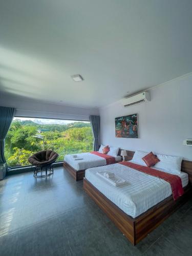 a bedroom with two beds and a large window at May Farm in Hương Hóa