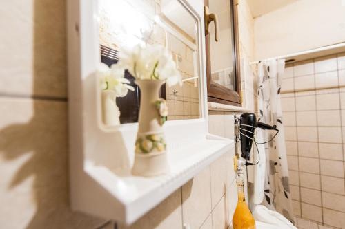a vase with flowers on a shelf in a bathroom at Antiche Corti in Scorrano