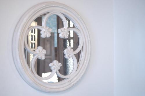 a mirror with a white frame with a window at Casa com Historia in Covilhã