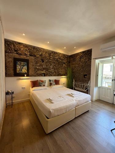 a bedroom with a large bed and a brick wall at Bibike in Catania