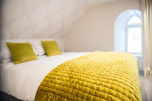 a bed with a yellow blanket on top of it at Heathmount Hotel in Inverness