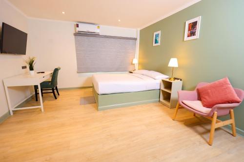 a bedroom with a bed and a desk and a chair at O'Shea's Sukhumvit Bangkok in Klong Toi