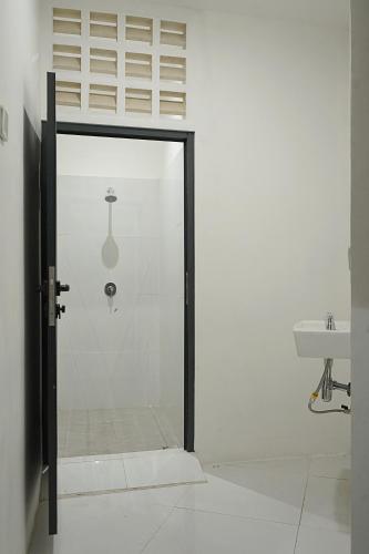 a glass shower door in a bathroom with a sink at New Hostel Braga in Bandung