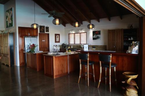 a kitchen with wooden cabinets and a bar with stools at Sea Winds Villas in Singatoka