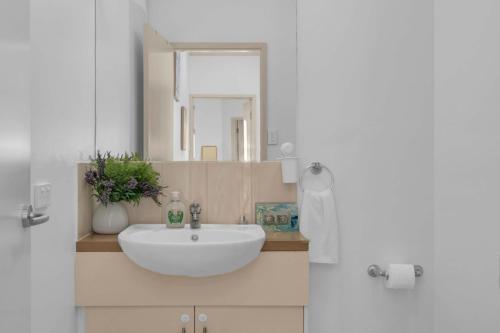 a bathroom with a white sink and a mirror at Modern Metro by Host Solutions in Mawson Lakes