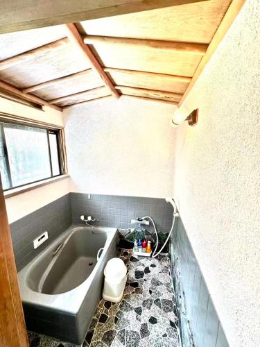 a small bathroom with a tub and a toilet at 古民家松 in Isumi