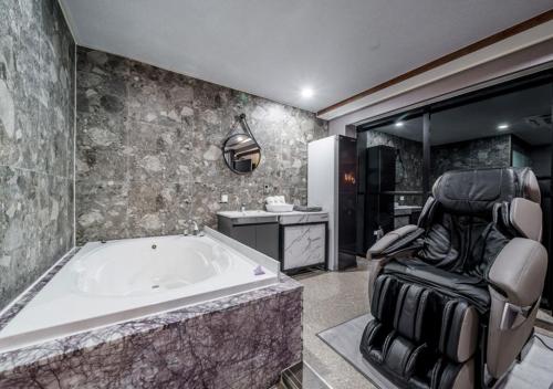 a large bathroom with a tub and a chair at G7 Hotel in Tongduch'ŏn
