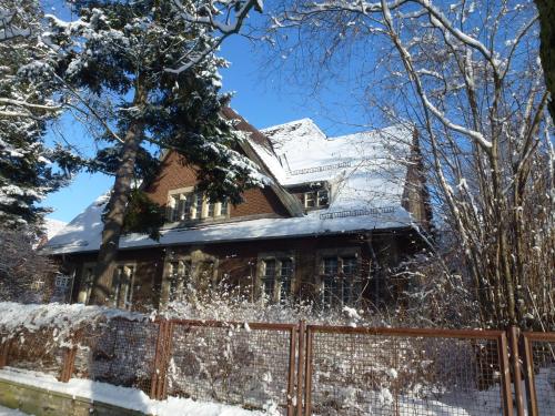 a house covered in snow with a fence at Villa-Hufeland in Berlin