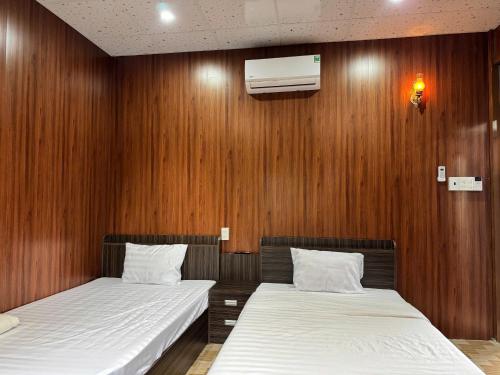 two beds in a room with wooden walls at Nam Anh Homestay in Bảo Lộc