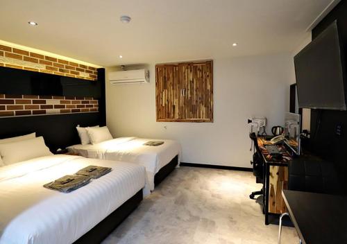 a hotel room with two beds and a desk at Incheon Illuwa Hotel in Incheon