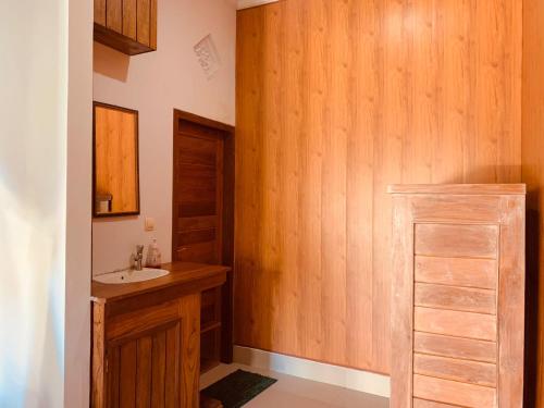 a bathroom with a sink and a wooden wall at Dika Homestay in Sidemen