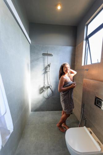 a woman standing in a bathroom with a toilet at Secret Paradise Edge in Weligama