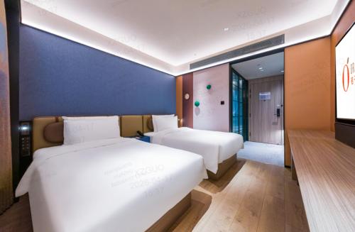 a hotel room with two beds and a television at Orange Hotel Shanghai Wuzhong Road Metro Station in Shanghai