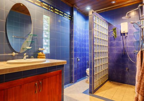 a blue tiled bathroom with a sink and a mirror at Villa Anahata in Ban Tai
