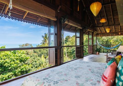 an open living room with a bed and large windows at Villa Anahata in Ban Tai