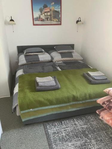 a bedroom with two beds with a green blanket at Tomi Apartman in Velence