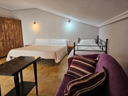 a hotel room with two beds and a couch at Hostal Restaurante Las Cavenes Del Cabaco in El Cabaco