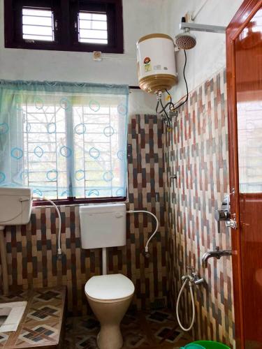 a bathroom with a toilet and a window at Green Stay,AC room in Sibsāgar