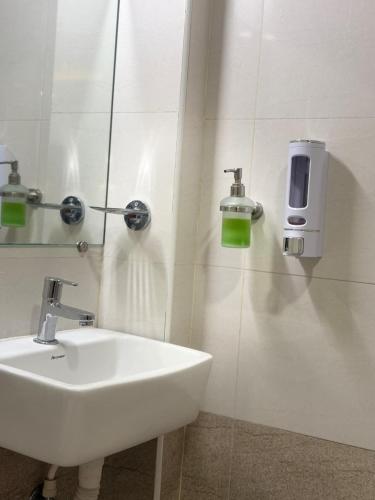 a bathroom with a sink and a soap dispenser on the wall at Yercaud Rathna Residency in Yercaud