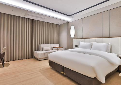 a bedroom with a large white bed and a chair at 대구 빌리언웨스턴호텔 in Daegu