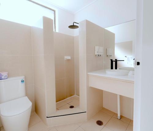 a white bathroom with a toilet and a sink at Canberra Park Motel in Canberra