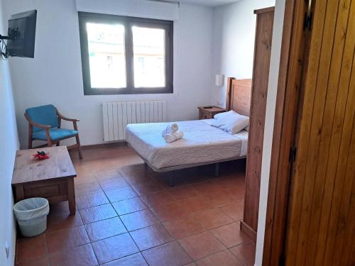 a bedroom with a bed and a chair and a window at Hostal Restaurante Monterde de Albarracín in Monterde de Albarracín
