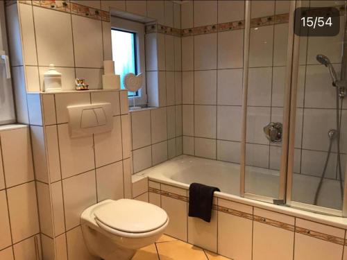 a bathroom with a toilet and a tub and a shower at Vina am Ring Apartment in Mannebach