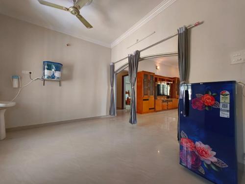 a living room with a ceiling fan and a refrigerator at Eesha Elite - Rameswaram in Rāmeswaram