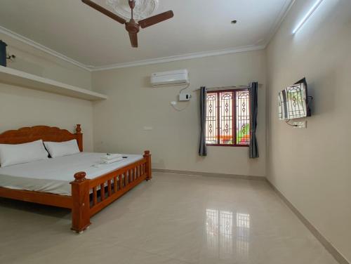 a bedroom with a wooden bed and a window at Eesha Elite - Rameswaram in Rāmeswaram
