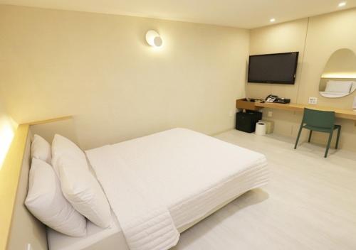 ein Hotelzimmer mit einem weißen Bett und einem Schreibtisch in der Unterkunft Chuncheon Pine Tree Hotel in Chuncheon