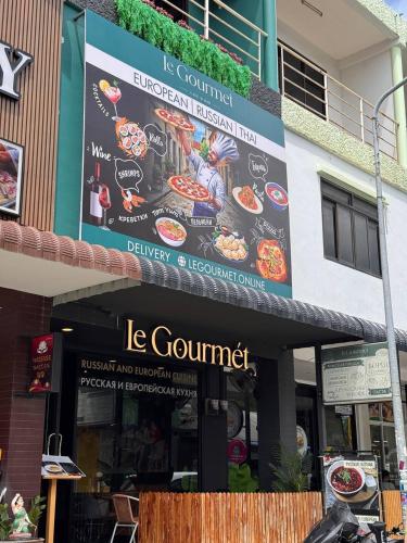 a building with a sign for a restaurant at Guest House LeGourmet in Kata Beach