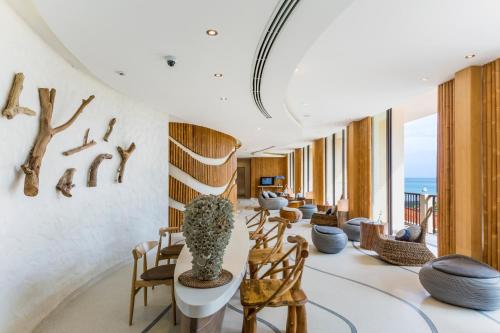 a lobby with chairs and tables and the ocean in the background at Bandara Beach Resort, Phuket in Panwa Beach