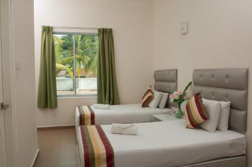 two beds in a room with a window at Akar Beach Resort in Port Dickson