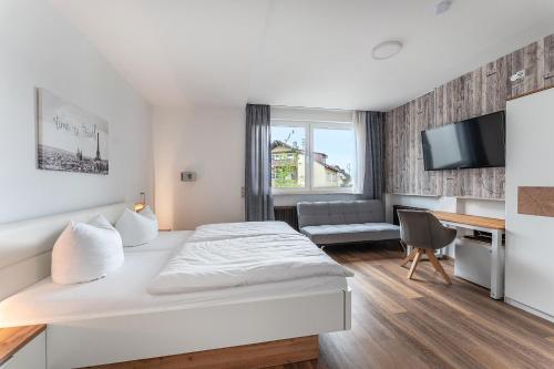 a bedroom with a bed and a desk and a tv at Hotel Glas Schwarzwald in Fluorn