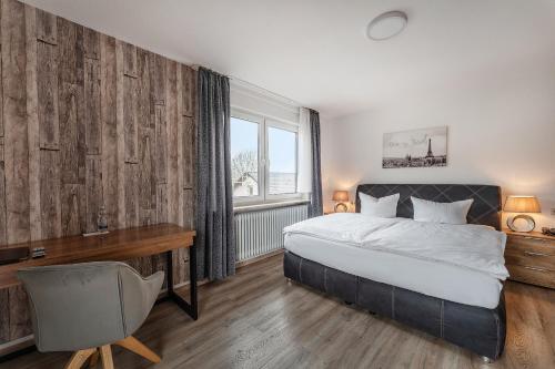 a bedroom with a bed and a desk and a window at Hotel Glas Schwarzwald in Fluorn