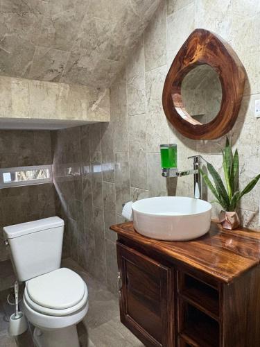a bathroom with a sink and a toilet and a mirror at Cocos House Zicatela in Puerto Escondido