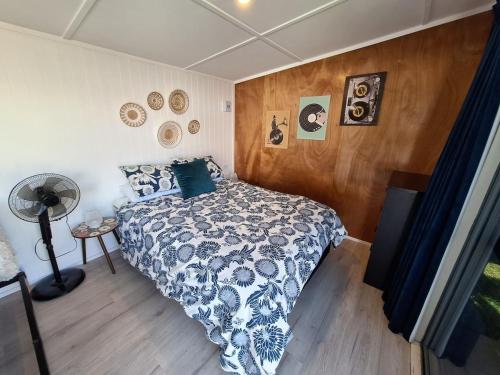 a bedroom with a bed and a wooden wall at Beach Pad in Whangamata