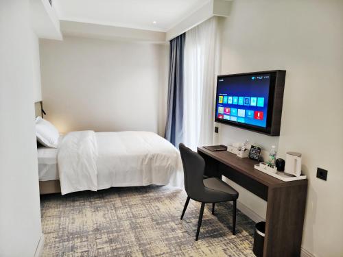 a hotel room with a bed and a desk with a television at Central Park Hotel 中央公园酒店 in Jalal-Abad