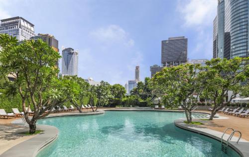 a swimming pool with trees in a city at Grand Hyatt Erawan Bangkok in Bangkok