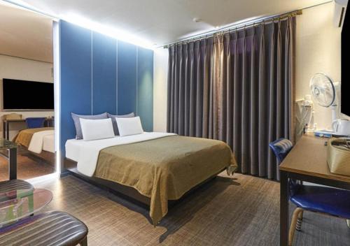 a hotel room with a bed and a desk and a room at Chuncheon Urbane Hotel in Chuncheon