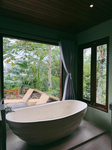 a bath tub in a room with a large window at Lira House by Yukaya Escape in Tegalalang