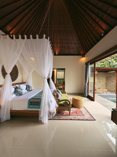a bedroom with a bed with mosquito netting at Lira House by Yukaya Escape in Tegalalang