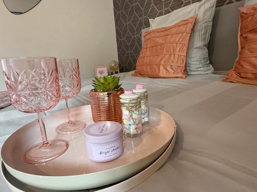a tray with two wine glasses and jars on a bed at Le nid des étoiles - Tram & Centre in Dijon