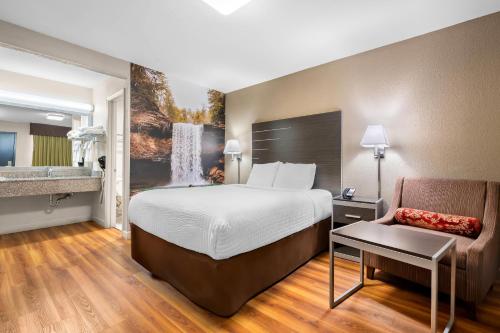 a hotel room with a bed and a chair at Clarion Pointe Athens I-65 in Athens