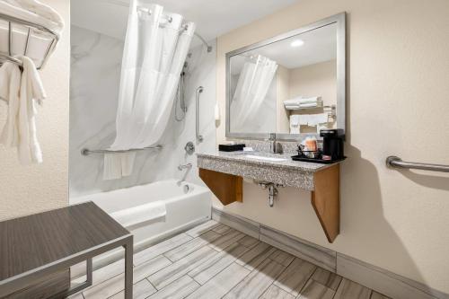 a bathroom with a sink and a tub and a mirror at Clarion Pointe Athens I-65 in Athens
