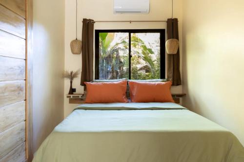 a bedroom with a bed with orange pillows and a window at Red Palm Villa in San Vicente
