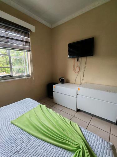 a bedroom with a bed and a flat screen tv at Monono Guesthouse in Bloemfontein