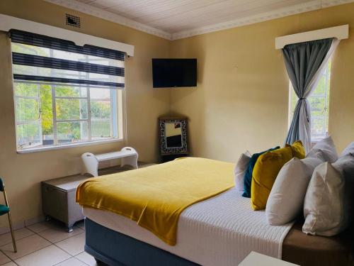a bedroom with a bed with a yellow blanket and a window at Monono Guesthouse in Bloemfontein