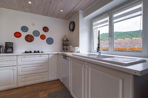 a white kitchen with a sink and a window at Gîte la Pigne in Aurel