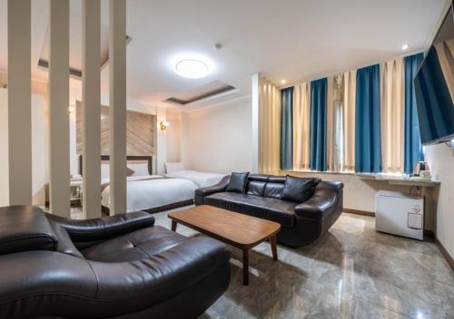 a hotel room with a couch and a bed at Ansan Seowon Tourist Hotel in Ansan